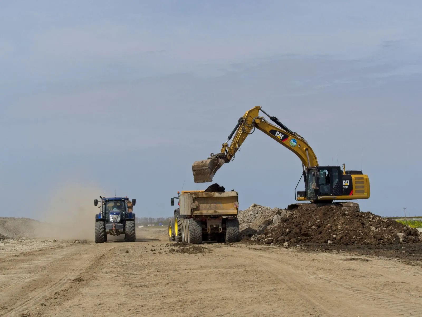 Excavator loading fill dirt into a dump truck
