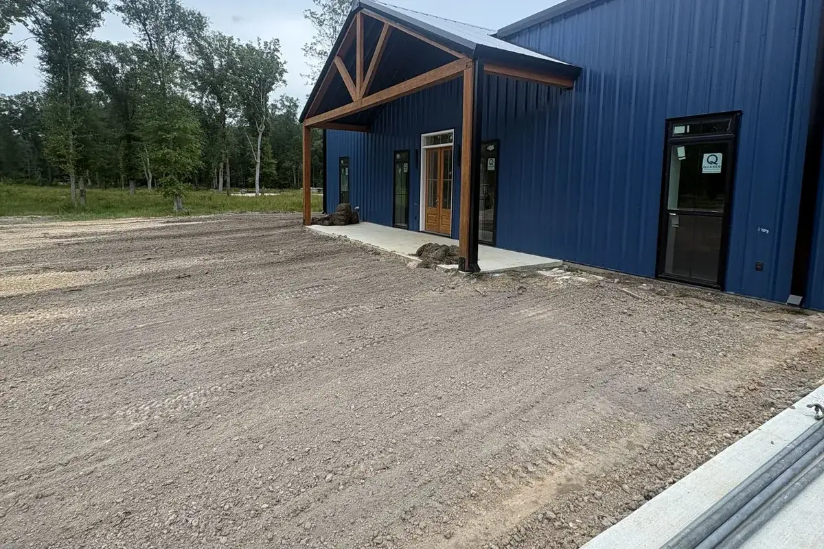 Graded ground along the front of a blue metal building near Hammond, LA