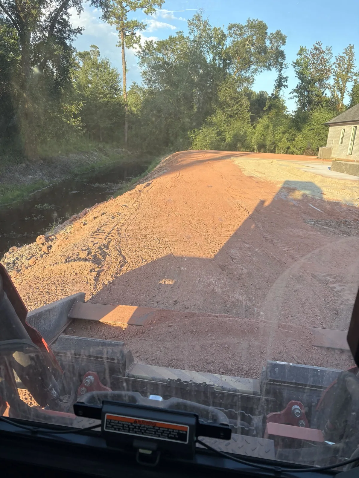 Freshly graded dirt pad seen from the skid steer seat on a home site near Hammond, LA