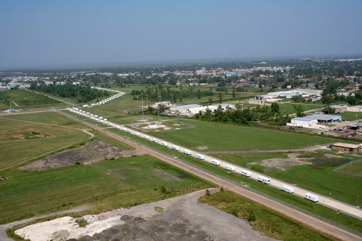Aerial view of flat, low open ground and graded roads beside the airport in Kenner, with the city spread out beyond